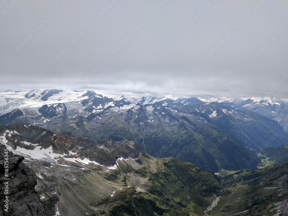 At the top of Mount Titlis where we can see the peaks of other mountains in the distance with ice glaciers formed on them.