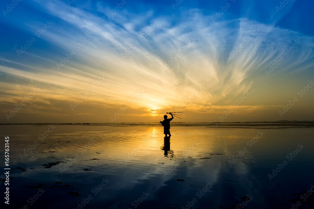 Minimal Silhouette of happy tourist with poles in hand above head on the beach with sunrise sky.