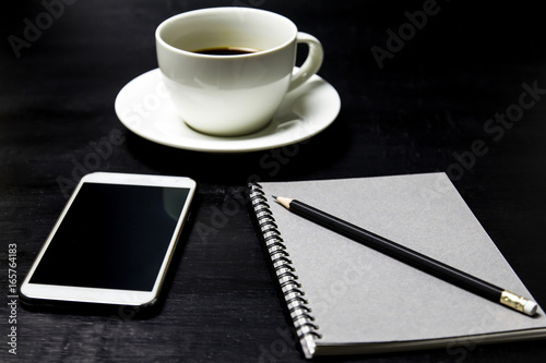 Coffee with notebook ,pencil and mobile phone on wood background.