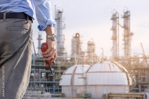 Industrial engineer stand in field of petrochem plant with the walkie-talkie