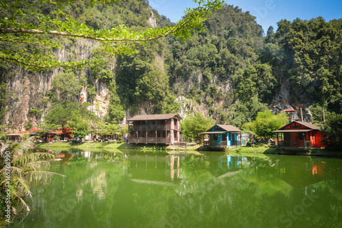 Fotografie Water reflections of wooden houses with limestones on the background in the countryside of Ipoh city, Perak, Malaysia