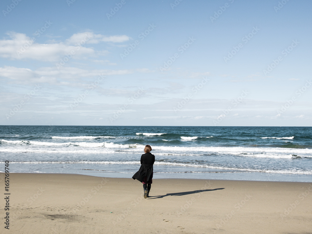 A woman walking towards the sea