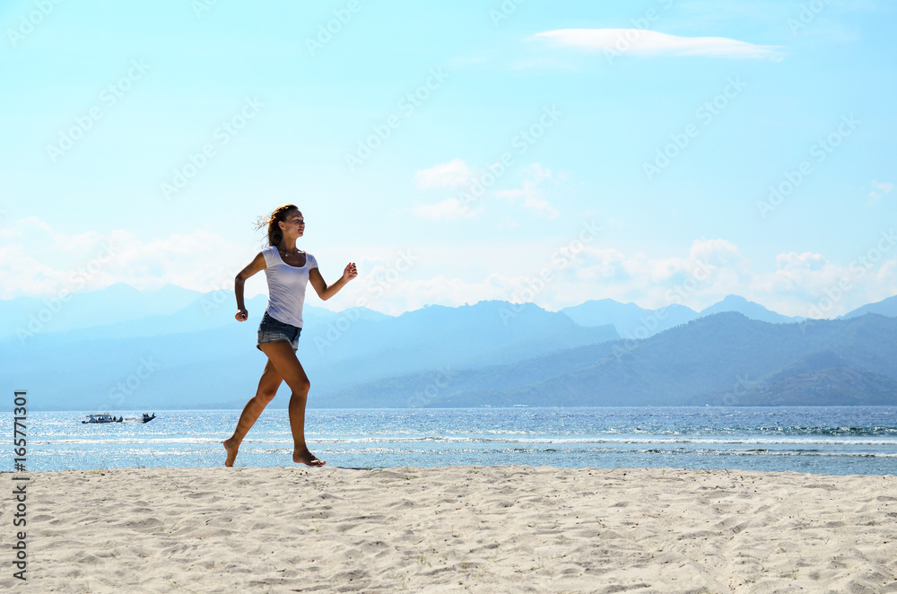 Woman jogging on the beach at sunset. Bali island, Indonesia