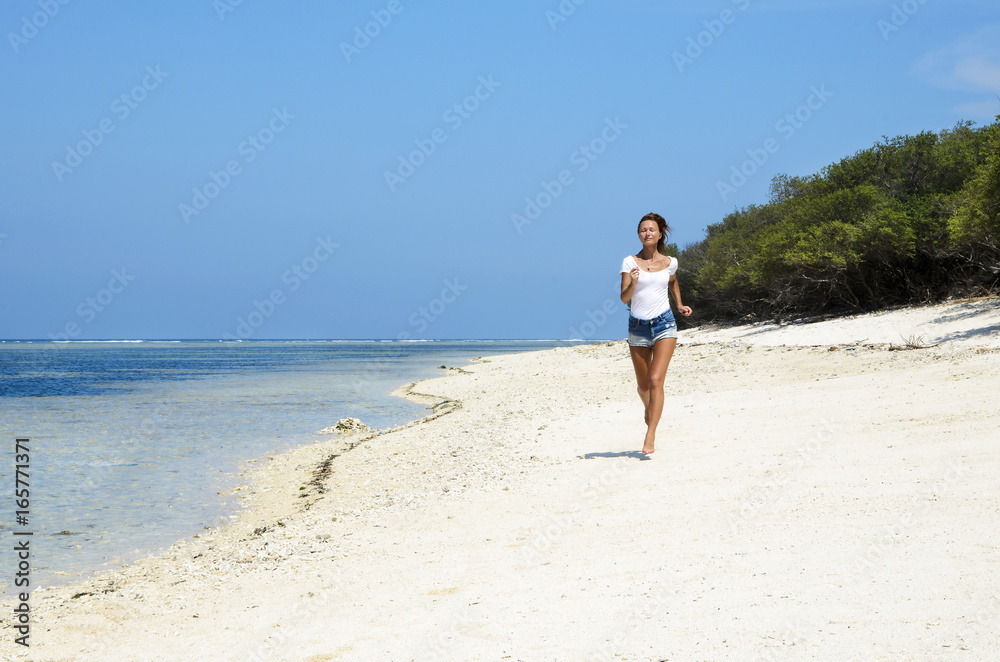 Woman jogging on the beach at sunset. Bali island, Indonesia