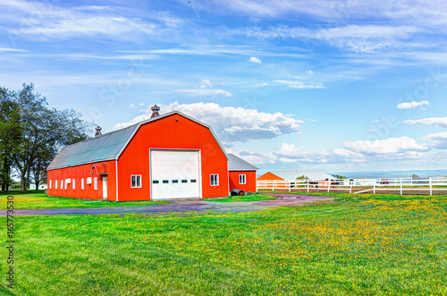 Red orange painted barn shed with white doors in summer landscape field in countryside