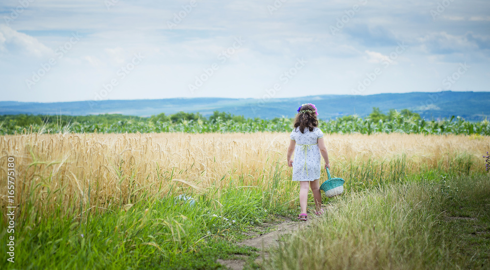 happy cute little girl in the wheat field on a warm summer day