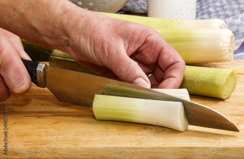 leek is cut with a kitchen knife on a wooden board