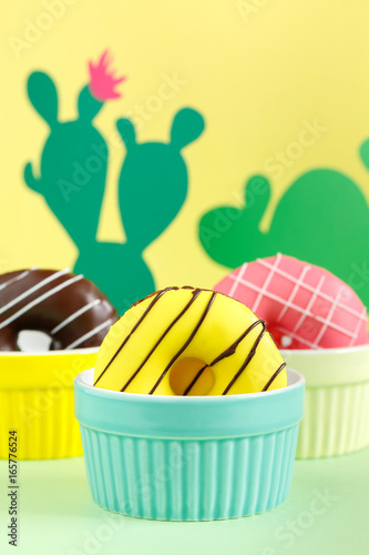 Close up donuts on a bright background.  Creative concept junk food. Paper cactus with flower. photo