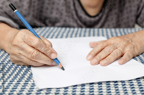 elderly woman writing on blank paper