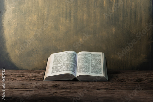 Bible and a crucifix on a old table. Beautiful gold background.Religion concept. photo