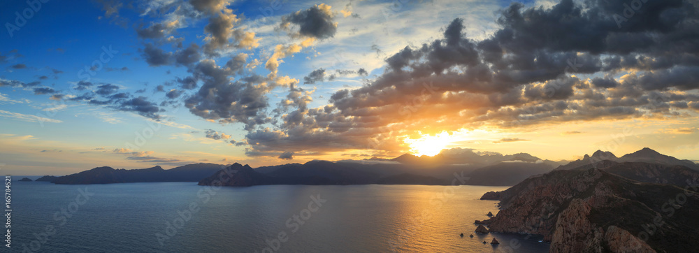Panorama of a summer sunrise over the sea and a beautiful mountain landscape. At Capu Rossu, on the island of Corsica, France.