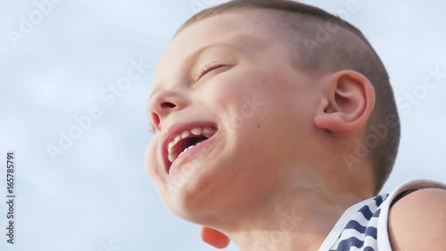 Funny happy smiling boy singing a song on sky background