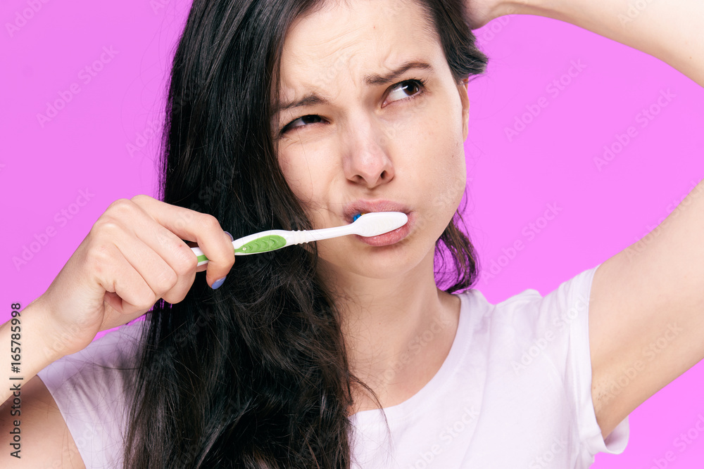 1226018 Young beautiful woman on a pink background cleans teeth, cleanliness 1226018 Young beautiful woman on a pink background cleans teeth, cleanliness