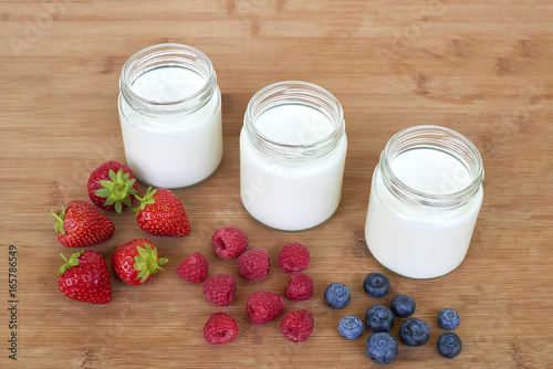 Three glass jars with yogurt and variation of berries - diagonally