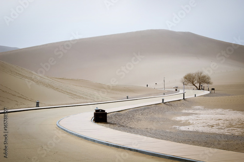 The road inside Mingsha shan desert and Crescent moon lake in Dunhuang, Gansu, China photo