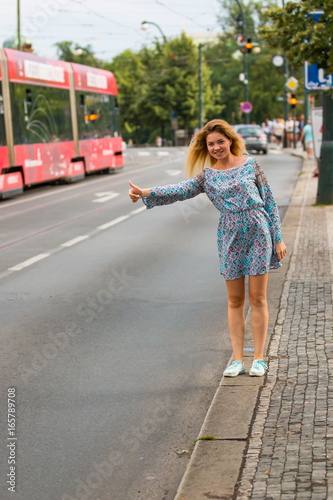 Young woman doing the hitch-hiking in a street of a city