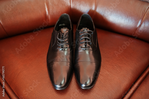Groom brown shoes on leather coach.