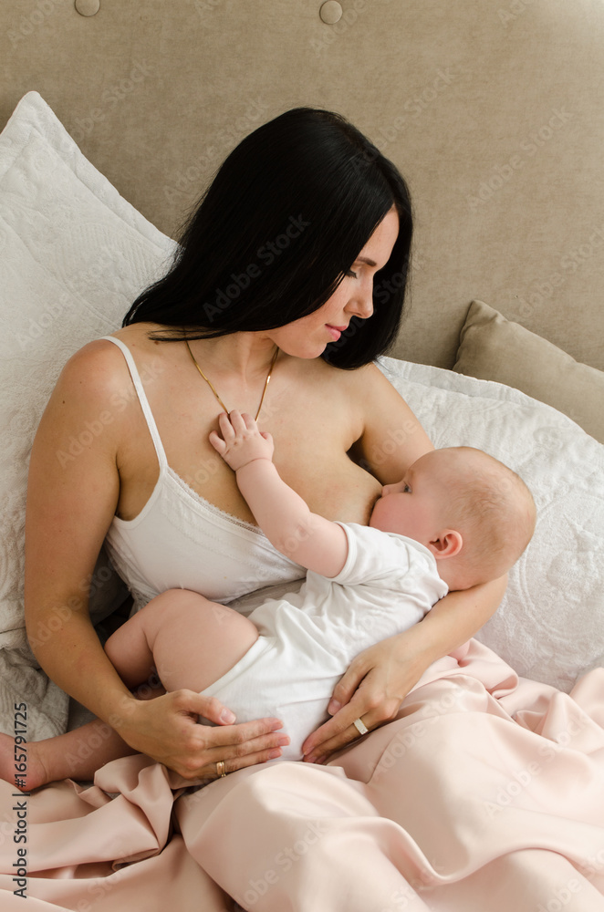 Breastfeeding. Young mother nursing baby. Family at home
