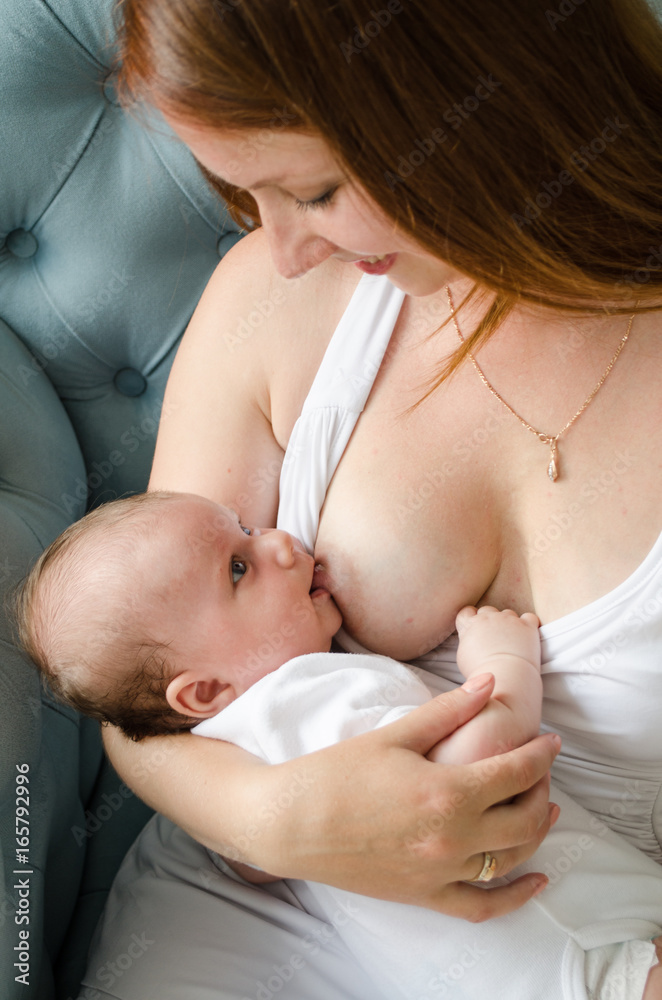 Breastfeeding. Young mother nursing baby. Family at home