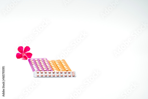 Contraceptive pills with pink flower on white background