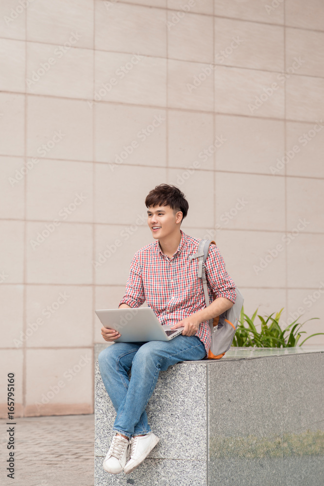 Male student using laptop in college campus Male student using laptop in college campus