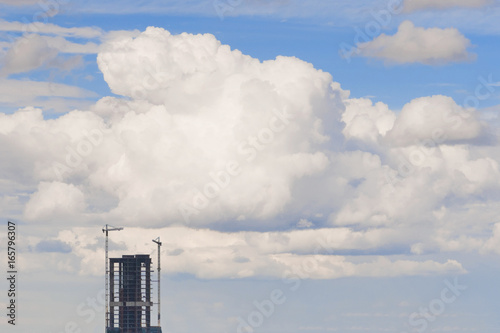 Cuadro en lienzo A high-rise building under construction against a background of a fluffy cumulus cloud