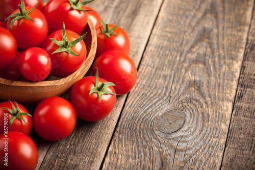 Fresh tomatoes in a wooden bowl on wooden table