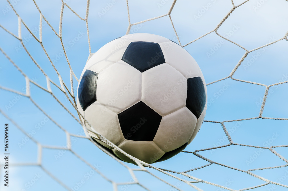 Soccer football in Goal net with the sky field.