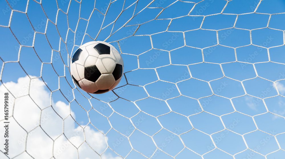 Fototapeta premium Soccer football in Goal net with the sky field.