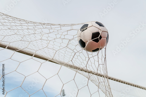 Soccer football in Goal net with the sky field.