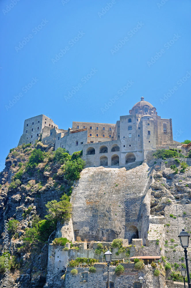 Aragonese castle on a cliff on the background of blue sky