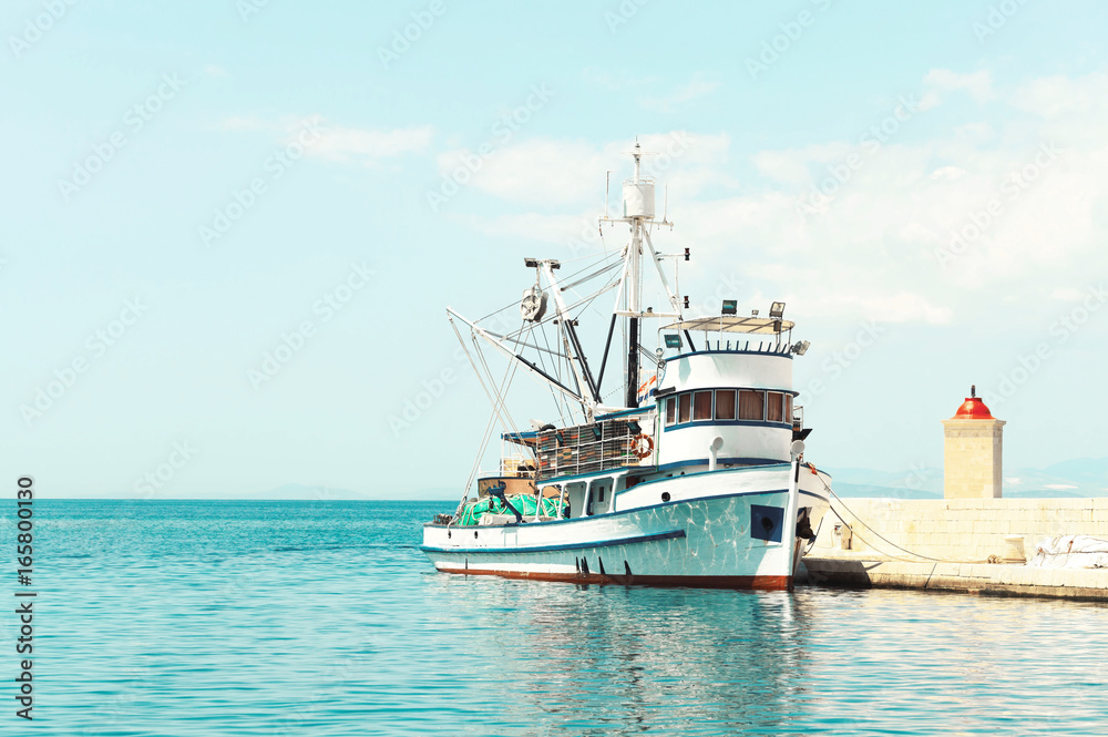 Fishing trawler at a pier next to a lighthouse