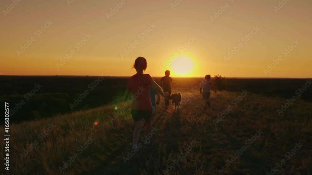 A group of children are running happily towards the sunset with the dog. Concept - a happy childhood, friendship. Slow motion video A group of children are running happily towards the sunset with the dog. Concept - a happy childhood, friendship. Slow motion video
