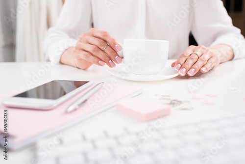 cropped shot of businesswoman with perfect manicure drinking coffee at workplace