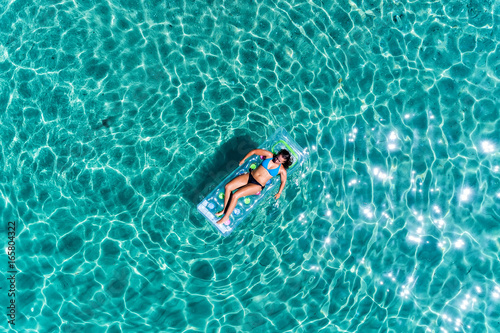 aerial view of a beautiful young woman in bikini on a matress in the sea