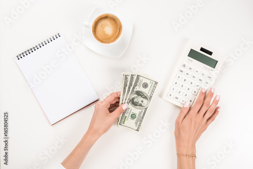 cropped shot of businesswoman working with calculator and dollar banknotes at workplace © LIGHTFIELD STUDIOS