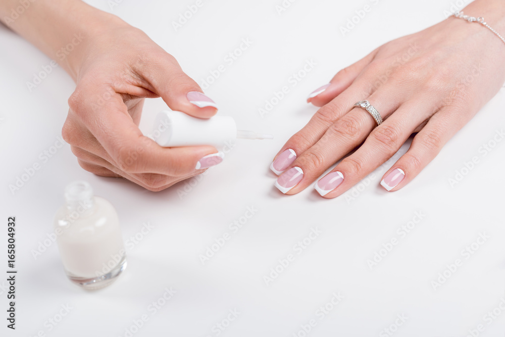 cropped shot of woman holding nail polish while doing manicure