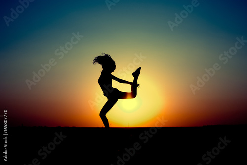 teen girl jumping at sunset. silhouette photo