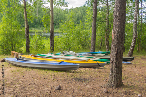 kayaks on the shore of a forest lake on a summer day.