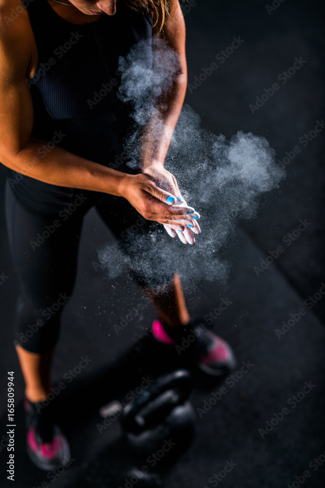 Woman athlete putting weightlifting chalk
