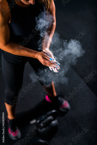 Woman athlete putting weightlifting chalk