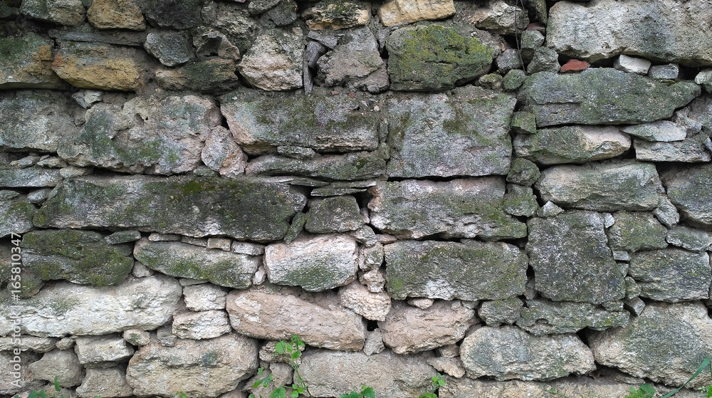 Old masonry of irregularly shaped green mossy stones. Aged stonework Old masonry of irregularly shaped green mossy stones. Aged stonework