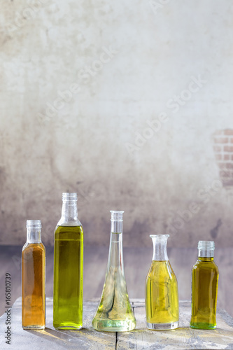 Various types of oil in bottles in a vintage wooden background