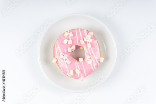 Donut covered with pink icing on white background.