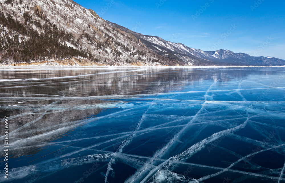 Beautiful winter landscape with mirror blue ice on the frozen Siberian Lake Baikal