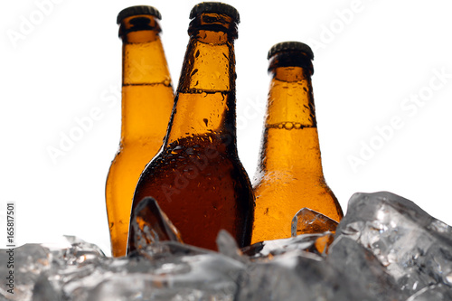 Three bottles of beer in ice cubes. Close up. White background