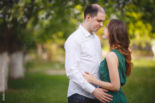 Couple in love: young girl in a long green dress and balding man in the garden. Spring or summer love story © Olga Mishyna