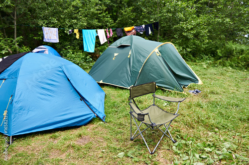 Folding camping chair and tent in meadow