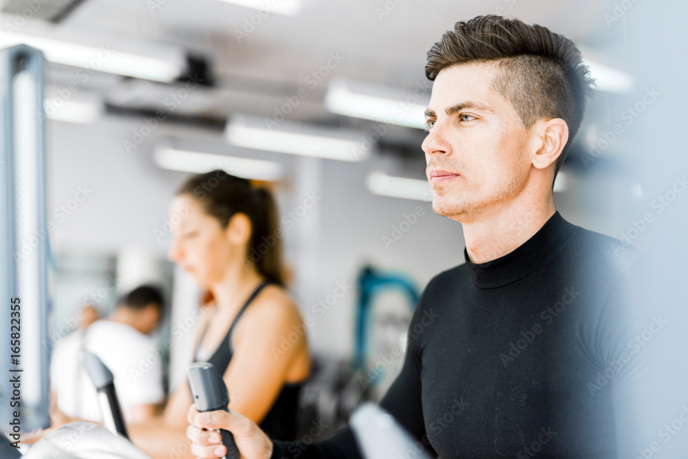 Group of healthy young people using treadmill and elliptical tra Group of healthy young people using treadmill and elliptical tra
