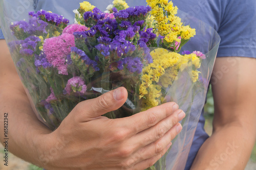 Quadro em tela Bouquet of violet, yellow, pink and white statis in the man's hands